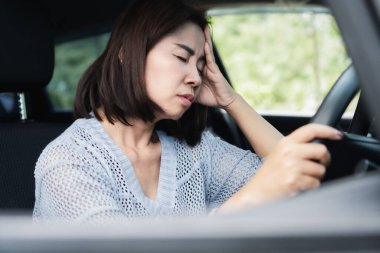 Asyalı bir kadın hasta, başı dönüyor ve araba kullanırken başı ağrıyor. Uzun bir yolculuktan sonra dinlenmek ve kaza yapmamak için arabayı durduruyor.