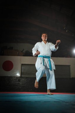Odaklanmış genç bir erkek dövüş sanatçısı geleneksel bir karate kata dizisini titizlikle ve disiplinle gerçekleştiriyor.