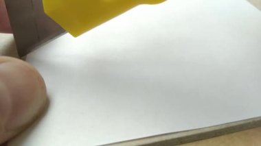 Closeup cutting a piece of paper using utility knife or office knife. Macro