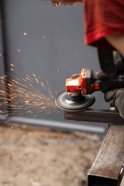 İş masasında metal profiliyle çalışan profesyonel bir kumaş işçisi. Endüstriyel atölyede elektrikli bir öğütücü var. Kesme ya da temizleme mümkün.