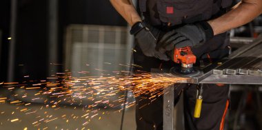 İş masasında metal profiliyle çalışan profesyonel bir kumaş işçisi. Endüstriyel atölyede elektrikli bir öğütücü var. Kesme ya da temizleme mümkün.