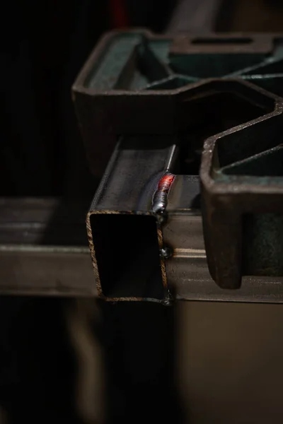 夹在特殊支架上的两个正方形铁管之间的红热焊缝 — 图库照片