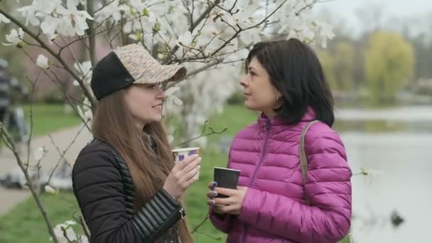 Две Девушки Пьют Кофе Разговаривают Парке — стоковое видео