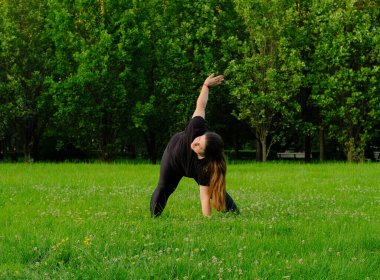 Tombul bir kız jimnastik yapıyor. Dışarısı ısınıyor. Sporcu doğada antrenman yapar. Genç bir kadın spor için parka gider. Şişman kız spor yapıyor.