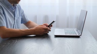 Erkek eli telefon kullanırken yakın plan görüntüsü. Erkek elleri ekranı akıllı telefondan araklıyor ve daktilo ediyor. Bir mobil cihaz kullanarak internette sörf yapma kavramı.