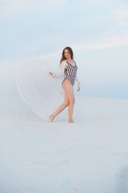 Sahilde gün batımında dans eden kaygısız kadın. Mutlu yaşam tarzı konsepti. Dans pisti, bohem kıyafeti, bohem tarzı. Romantik, mutlu, hafiflik hissi