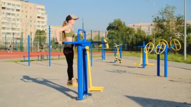 Dışarıda egzersiz yapan genç bir kadın. Egzersiz makinesi kullanıyor.