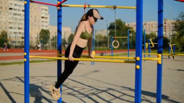 Egzersiz makinelerinde spor yapacak bir kız. Sokaktaki platformda egzersiz makineleri.