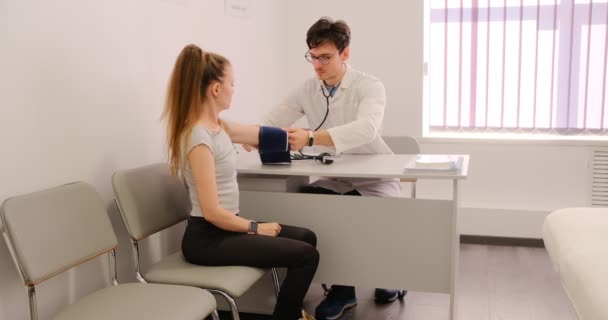Genç Bir Erkek Doktor Bir Klinikte Tonometre Kullanarak Hastaların Tansiyonunu — Stok video