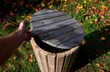 Ahşap çöp tenekesi. ahşap kaplı. Panelleme. Tümsekli silindirik bir şekil. Eşleşen mobilyaları ve çimenliği olan doğal park