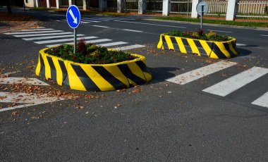 Arabaların arasındaki parka giden yolda park engeli var. Yaya geçidindeki araçların önünde yaya koruması, terörizme karşı bariyer, ok, mavi, çiçek, toprak, toprak