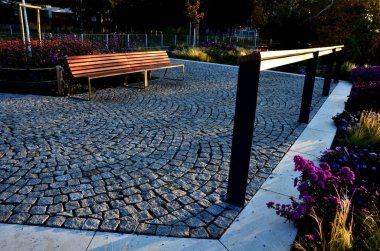 Sonbahar çiçekleri, uzun ömürlü otlar ve siyah taş kaldırımlı bir meydanda, granit kaldırımlar, sonbahar mor beyaz ve sarı astlar ve şehir parkında adaçayı ile süslenmiş otlar.