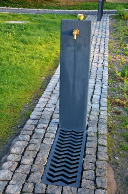 Net bir iple metal bir kapıdan ayrılan bir çocuk parkında. Ahşap ve gri betondan yapılmış çitler. İdrara, yürüyüşe çıkan köpeklere ve sahiplerine karşı oynamak için kum havuzunun korunması