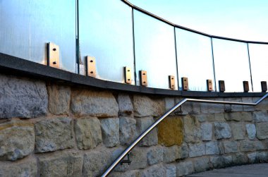 Cam panellerden oluşan lüks bir evin parmaklıkları gri metal paslanmaz çelik panellerle bağlanmış. Sütlü buzlu cam bariyer havadar bir izlenim veriyor. cilalanmış metal kaplama