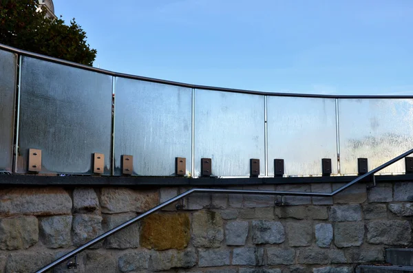 railing of a luxury house consisting of glass panels fastened with gray metal stainless steel paneling. the milky frosted glass barrier gives an airy impression. polished metal cover