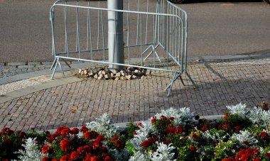 Pembe-turuncu bir çiçek kombinasyonu olan çılgın yıllık yatak. Çeşmenin yanındaki meydanda yuvarlak kum taşından duvarlar var. Sıra dışı bir renk şebekesinde çiçek halıları