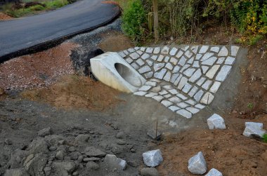 Yeni inşa edilmiş bir yol, üst üste dizilmiş perdeli ve asfalt halı katmanlarını görebilirsiniz. Çevresindeki alan beton oluğu olan bir hendeğe saplanmış. yağmur suyu drenajı