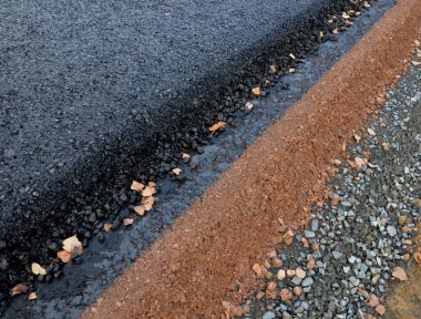 Yeni inşa edilmiş bir yol, üst üste gelen perdelenmiş ve asfalt kaplama ve delinme katmanlarını görebilirsiniz. Kenar, hendekteki toprak tarafından yavaş yavaş şekillenir, tamamlanmamış, düşer. 