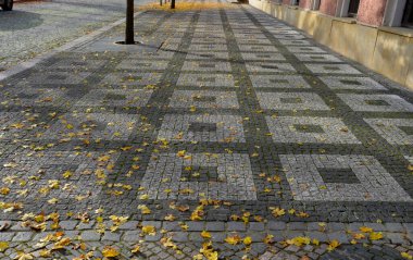 Şehir sokaklarında gezinen mozaik kaldırım taşları mermer döşeme şekiller, çelik parmaklıklarda sokak linden insanlar kaldırımda yürüyor.
