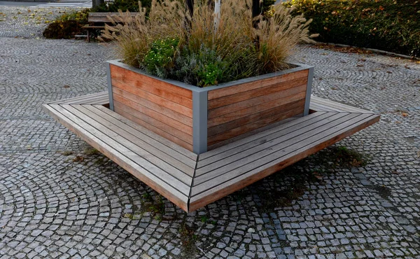 stock image a square flower pot on the walls of which are benches made of planks. suitable for the rainy square and promenade of the spa park. luxury wooden furniture, steel frame, metal gray