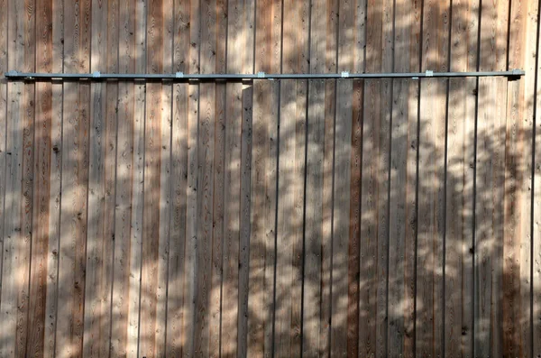スキッドレールに沿って側面に引っ張ることができる板で作られたドアや納屋のドア ドアは車輪付きのヒンジにかかっています コテージの木で作られた格納式のシャッター — ストック写真