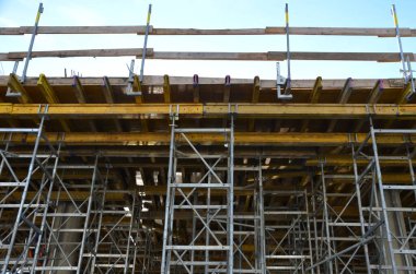 Güçlendirilmiş çelik betondan yapılmış evler depreme dayanıklıdır ve birkaç kat yüksekliğinde olabilirler. Tel örgü örülür ve karıştırıcıdan beton dökülür, mavi gökyüzü, merdiven, kırmızı, çubuk, döküm 