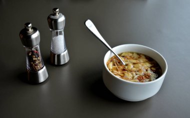 Kasede kaşık, restoranda gri masada çorba. Tuz ve biber yiyeceği tatlandırır. Erişte tavuklu porselen kase, çorba. Avusturya 'daki bir dağ kulübesinden güzel bir tat.