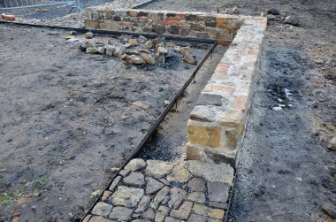 Taş kaldırım, iki çelik kaldırım taşının arasındaki çakıl döşemesinde kurumuş. Kum taşı ve yanmış tuğla parçaları kırsal bir his veriyor. Bitki bahçesindeki dar park yolları, alçak, tutucu, yanmış