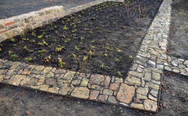 Taş kaldırım, iki çelik kaldırım taşının arasındaki çakıl döşemesinde kurumuş. Kum taşı ve yanmış tuğla parçaları kırsal bir his veriyor. Bitki bahçesindeki dar park yolları, alçak, tutucu, yanmış