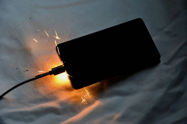 stock image connected to charger in socket. never charge battery overnight, there is risk of battery catching fire, unattended transformer. skin burns when saving property, disconnecting from electric source