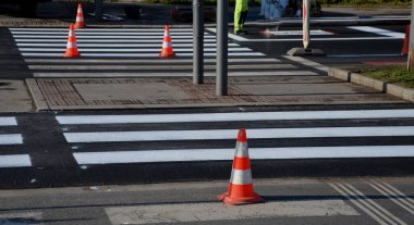 Kavşakta kavşak ve kavşakta yatay işaretler düzeltiliyor. Şablon kullanarak yeni semboller püskürtüyorlar. Sonra onu kum pigmentiyle kaplıyorlar. Tekerlek değil, yansıtıcı yeşil giysi.