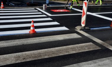 Kavşakta kavşak ve kavşakta yatay işaretler düzeltiliyor. Şablon kullanarak yeni semboller püskürtüyorlar. Sonra onu kum pigmentiyle kaplıyorlar. Tekerlek değil, yansıtıcı yeşil giysi.