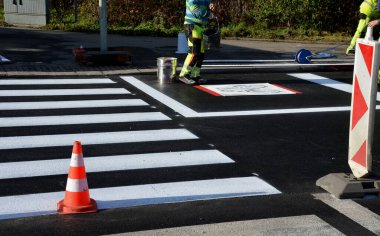 Kavşakta kavşak ve kavşakta yatay işaretler düzeltiliyor. Şablon kullanarak yeni semboller püskürtüyorlar. Sonra onu kum pigmentiyle kaplıyorlar. Tekerlek değil, yansıtıcı yeşil giysi.