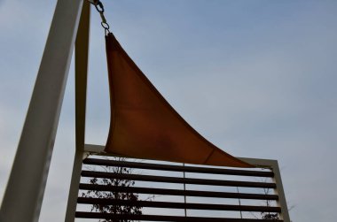 Sarı tuval gerildi, restoranın terasında güneş ve yağmurdan gölgelendi, çocuk parkında, gezinti alanında. Tahta gri kirişli pergola, beyaz metal çelik üzerinde, bağlanıyor, bağlanıyor, bağlanıyor