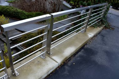 Çatıdaki otoparkın beton duvarında paslanmaz çelik parmaklıklar var. Tavan arasına çivilenmiş vidalar. Metal levha yağmur suyunu boşaltır. Çelik tel çocukların düşüşüne karşı örgü