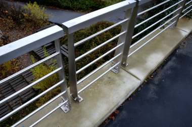 Çatıdaki otoparkın beton duvarında paslanmaz çelik parmaklıklar var. Tavan arasına çivilenmiş vidalar. Metal levha yağmur suyunu boşaltır. Çelik tel çocukların düşüşüne karşı örgü