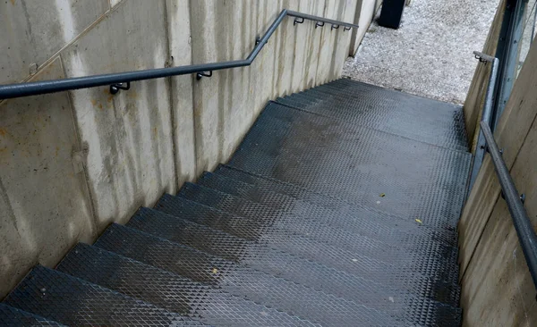 混凝土墙 中间有一个有防滑花纹的金属楼梯 外露的混凝土栏杆漆成黑色 — 图库照片