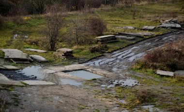Savaş bölgesinde bir sürü beton engel ve tuzaklarla dolu çamurlu bir yol. Askeri eğitim sahasında su birikintileri ve rutinler var. Üst görüş, askeri eğitim gözlemevi, ukra