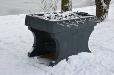 Parktaki genç masa futbolcuları için bir cazibe. Sahildeki deniz kenarı mobilyaları. Çekim kontrollü plastik dayanıklı masa. Aralıklı kar fırtınası ile kaplı