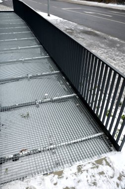 Endüstriyel salonda, ağır yüklenmiş çelik zemin ızgara ve parmaklıkların altında bile yüksek dirençle dolu dik bir merdivenin yan kapısı var. Genişletilmiş metal, güvenlik merdivenlerinin kenarları, siyah