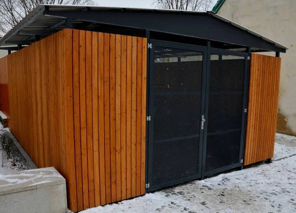 garage with wooden paneling and transparent mesh door. bin storage near the boarding house. protects citizens\' property and order in the closed shelter. car parking safe and without snow