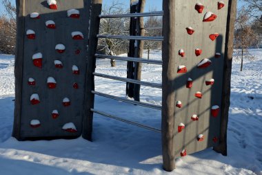 Parktaki oyun parkının duvarına tırmanmak. kaya, köprü, tünel, mavi gökyüzü için bileşik malzemeden yapılmış renkli taşlardan yapılmış tırmanma tutacakları olan katı kirişler.