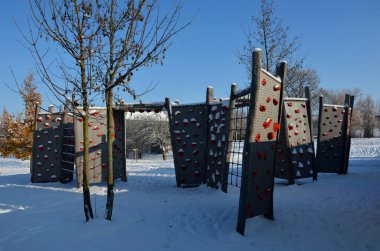 Parktaki oyun parkının duvarına tırmanmak. kaya, köprü, tünel, mavi gökyüzü için bileşik malzemeden yapılmış renkli taşlardan yapılmış tırmanma tutacakları olan katı kirişler.