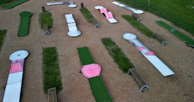 Parktaki mini golf sahası engelin arkasında golf topu yakalıyor. Emeklilik evi, yaşlılar, maaşlar, oyun, turizm, sahil, kum, tatil köyü, otel, apartman, daire