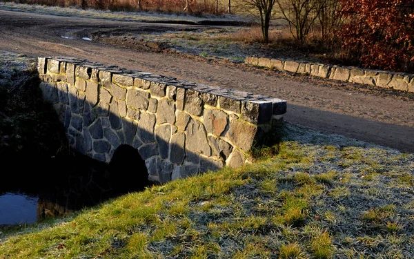 Drainage drainage reclamation channel is an outdated way of lowering the groundwater level. dam made of gray stones. supplies water to irrigate fields. stone bridge, dirt road gray gravel