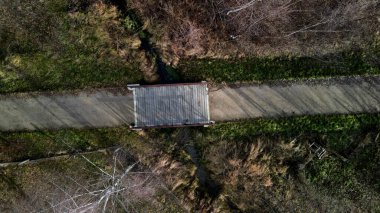 Ahşap korkuluklu bir park köprüsü dereyi geçiyor. Kirişler beton bir temeli tutan çelik bir kirişe sabitlenmiş. Çakıl yolu köprünün önünde, üstte, üstte