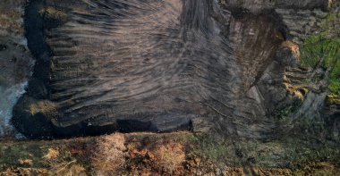 Ceset nakliyesine sahip eklemli bir kamyon eski bir madene ya da çöplüğe toprak boşaltıyor. Tahıl tarlasından geçen toprak yol. Büyük toprak setleri ve iyi toprak yığınları, sabah, inşaat alanı