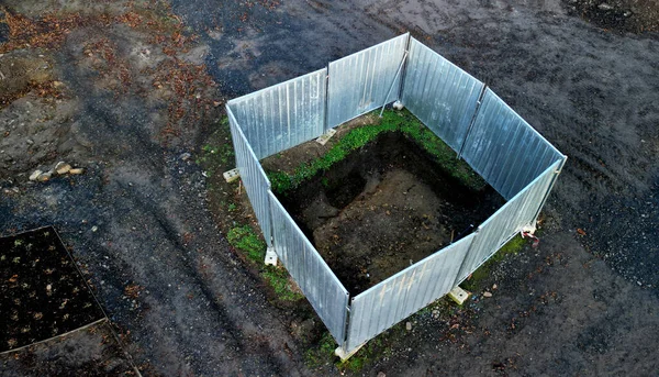 Excavation in park. a square hole testifies to archaeologist\'s find. The excavation pit is fenced with galvanized sheet fence that is foldable and mobile. it comes together piece by piece, dirt, soil