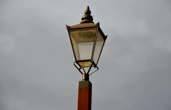Historicizing style of lamp that is not gas but LED lights. Lantern frame without glass filling. historic city center with natural facade brown wooden windows with arch