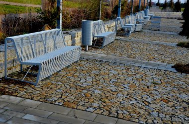 arched pergolas made of gray metal frames for climbing plants. benches and chairs of transparent wire furniture. dry garden walls and tall ornamental grasses sandy paths, sunlight, sunset, perennial